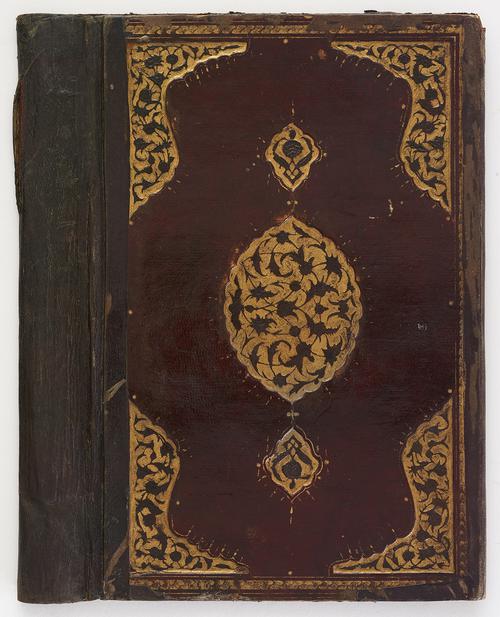 Back of burgundy leather bookbinding, spine of the binding has visible wear. A gold gilt-stamped medallion in the centre, and similar corner pieces. 