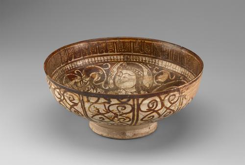View of a circular bowl, decorated in brown paint over a cream background. The base is small and raised. The inside shows a man on a horse, with a band of arrows below a band of script decorating the rim. The outside is decorated with brown swirls.