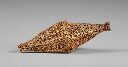Side view of Biconical hollow gold bead with filigree and granulated decoration, each face of the faceted cone with paired wires and granulation and a border of 'S' loops of plain wire, the top and bottom of the bead with a collar granulated decoration.