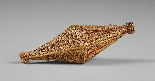 Side view of biconical hollow gold bead with filigree and granulated decoration, each face of the faceted cone with paired wires and granulation and a border of 'S' loops of plain wire, the top and bottom of the bead with a collar granulated decoration.
