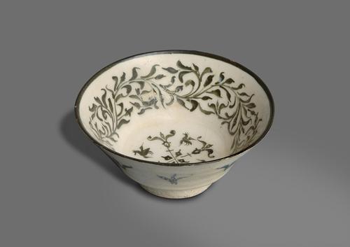 Bowl with flaring walls and black rim, the white frit body painted with a band of folage design in black around the interior walls, a central motif with split palmettes and flying birds. Flying birds on the outside walls.