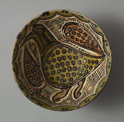 Dish, decorated with a large, plump bird, red, yellow and ochre with black spots, filling most of the bowl’s interior. The rim is decorated with ochre scalloping and dark brown dots.