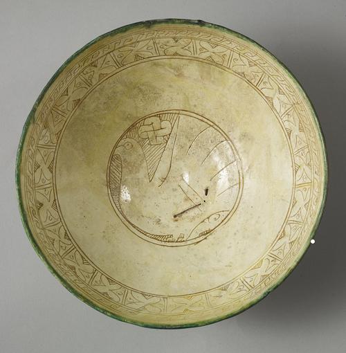 Bowl, buff and reddish clay body. In the central medallion, a nesting bird faces left against a ground of short, diagonal lines. Over the bird’s back is a pretzel-shaped ornament. At the rim, is a band of X’s, enclosed in small rectangles.