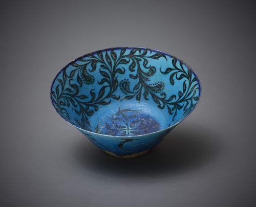 Bowl with flaring walls stepped down to a straight vertical foot with a foliage design painted with black under a transparent turquoise glaze. The central motif of eight fish swimming in an anti-clockwise direction, cobalt staining to the rim.