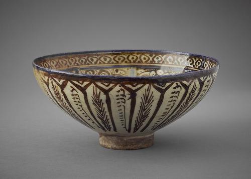 Bowl decorated in blue and brown lustre on a white ground. Just under the blue rim is a band ofbrown leaf ornamentation. The underside is decorated with narrow, brown frames containing wheat and grass stalks.