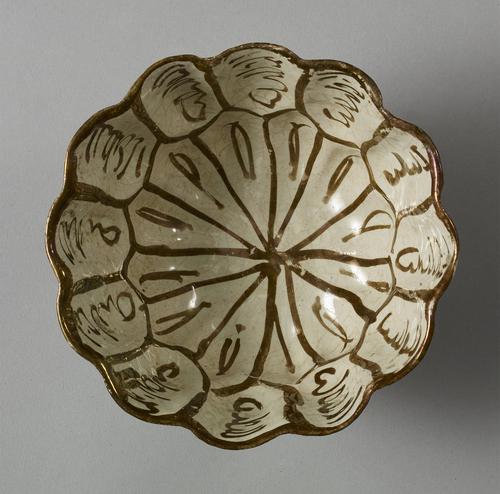 Bowl with bumped out lobes, decorated in brown lustre. On the interior, the centre and lower zones form a rosette, while the upper zone lobes contain short bands of illegible naskhi script.