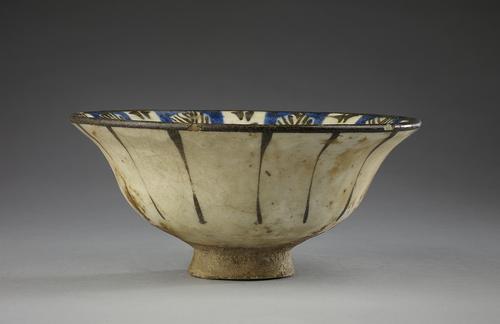 A blue, black and white-glazed pottery bowl, the white exterior with vertical black lines.