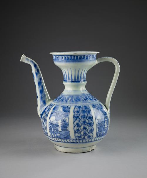 Blue and white pitcher, wide flaring top and a bulbous body. A band of blue dots circles beneath the rim, a wider band of painted "leaves" circles the neck. Around the shoulder is a band of blue "leaves". The body is divided into eight panels.