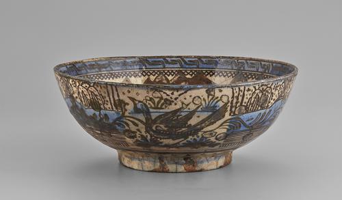 One of six panels two two scenes of approximately equal size on the exterior of this bowl. This scene shows a less lush landscape dominated by a large bird. The drawing is in brown on a cream ground with some light blue colouring for water and some elements of the landscape.