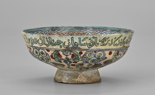 Side of ceramic bowl decorated with Arabic calligraphy and floral designs.