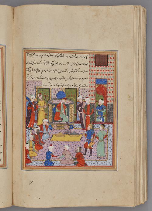 Painting within a rectangular border of blue, gold, green, and red, lines of script at the top and bottom. Courtly audience in front of a seated crowned figure.   