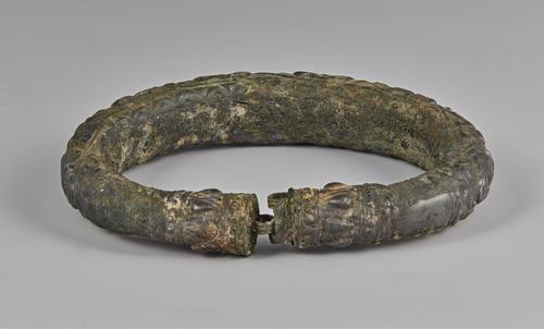 One of two silver arm bracelets, engraved, the back of the bracelet shows the clasp or connection and inside of the bracelet. Showing signs of corrosion on all sides.