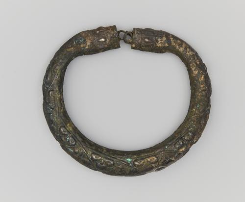 One of two silver arm bracelets, engraved, the top bracelet shows the clasp or connection and top. Showing signs of corrosion on all sides.
