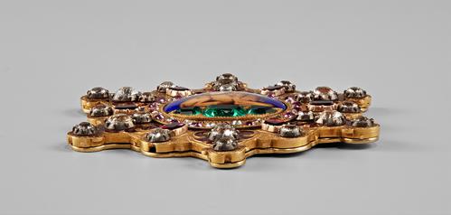 Side view and edge of the six-pointed openwork star, set with diamonds and other precious gemstones, predominantly rubies. The central enameled medallion features a lion laying down with a sun rising behind its back in the centre.