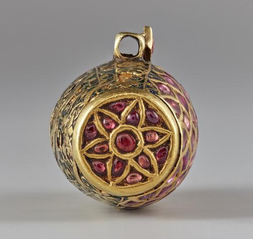 Cylindrically-shaped pendant view of the circular end with a six pointed star or flower pattern set with ruby’s.