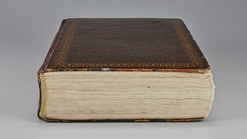 Side of closed manuscript showing cream-coloured pages and lacquered cover.