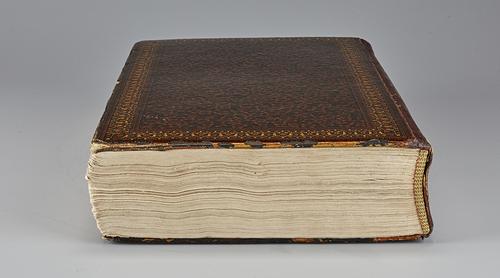 Side of closed manuscript showing cream-coloured pages and lacquered cover.